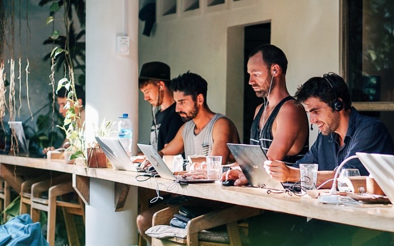 People working on laptops at a coworking counter in Bali