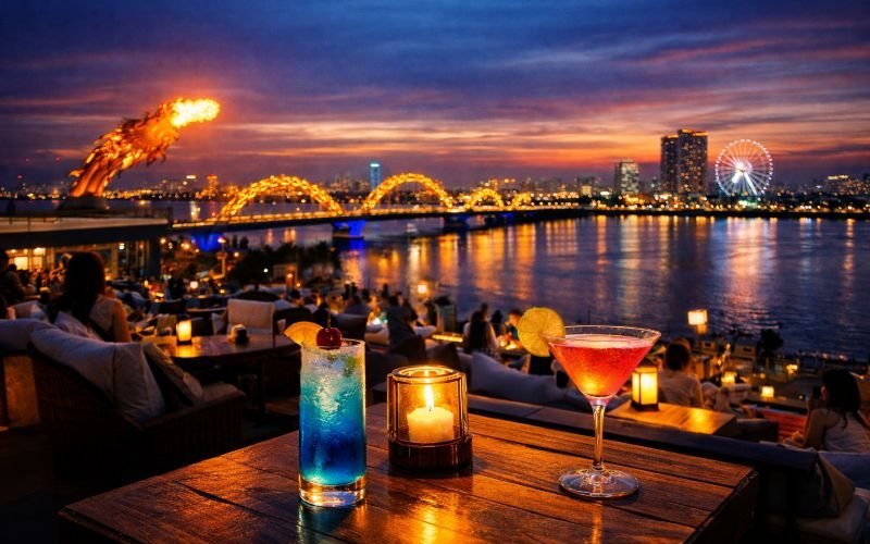 Rooftop bar on the Han River in Da Nang at dusk, with the Dragon Bridge lit up and breathing fire