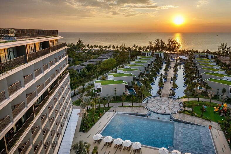 A laptop on a resort terrace facing the sunset over Long Beach, Phu Quoc