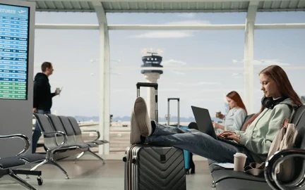 Traveller working on a laptop at an airport departure gate
